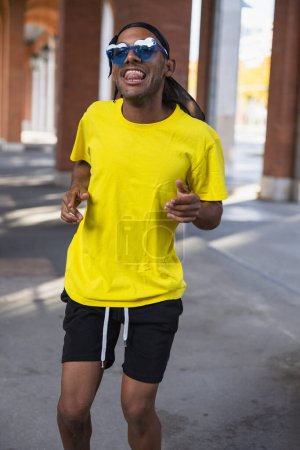Téléchargez les photos : Jeune garçon noir souriant joyeusement dansant dans la rue en appréciant la danse, photo verticale - en image libre de droit