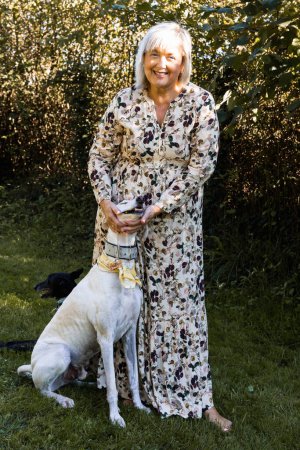 Foto de Portrait of beautiful woman enjoying the countryside while caressing her faithful white greyhound - Imagen libre de derechos