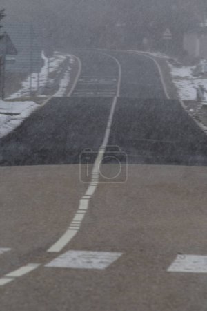 Téléchargez les photos : Détail d'une route vide avec chute de neige, photo verticale - en image libre de droit