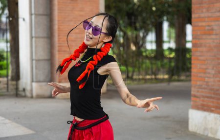 Photo for Picture of Asian woman with modern clothes and hairstyle dancing in the street, copy space - Royalty Free Image