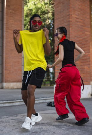 Foto de Una serie de imágenes que capturan la energía alegre de dos parejas de baile en vibrantes trajes de calle, compartiendo un baile y un cálido abrazo en la acera. - Imagen libre de derechos