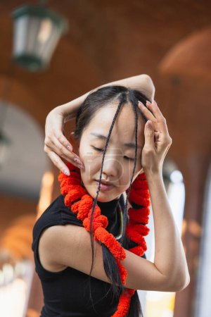 Photo for A young dancer with a vibrant red scarf closes her eyes in a moment of focus before an urban dance session. - Royalty Free Image