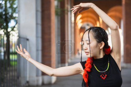 Téléchargez les photos : Danseuse captivante dans un cadre urbain, démontrant une pose de danse délicate d'inspiration orientale - en image libre de droit