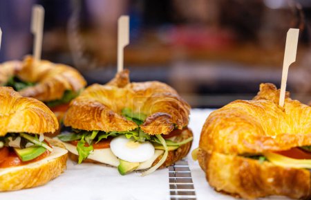 Foto de Sandwiches de croissant recién hechos con queso, tomate, huevo y verduras en exhibición. - Imagen libre de derechos