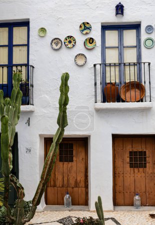 Foto de "Coloridas placas de cerámica adornan un edificio blanco con adornos azules en el encantador pueblo de Frigiliana, España." - Imagen libre de derechos