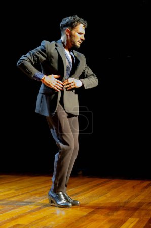 Téléchargez les photos : "Danseuse de flamenco masculine à l'expression intense se produisant sur une scène en bois, vêtue d'un costume classique." - en image libre de droit