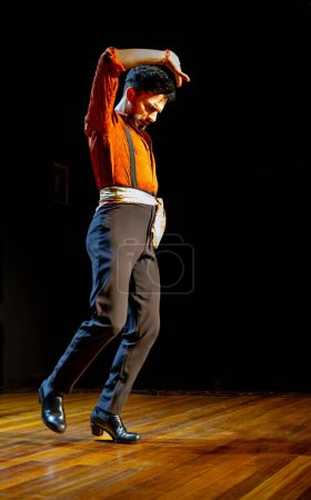 Photo for A male flamenco dancer caught in a moment of passion during a stage performance, with dramatic lighting highlighting his movement, vertical photo. - Royalty Free Image