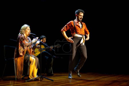 Foto de "Una bailarina de flamenco en movimiento, con un cantante y guitarrista interpretando, captura la esencia del flamenco español." - Imagen libre de derechos