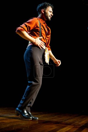 Téléchargez les photos : "Danseuse de flamenco en chemise orange vif incarne l'esprit de la danse avec une performance solo passionnée." - en image libre de droit