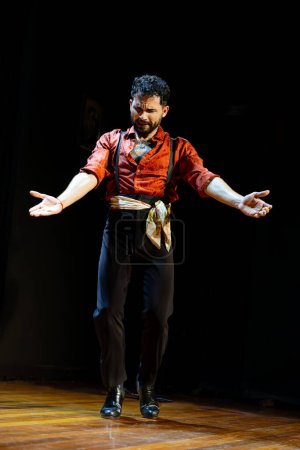 Téléchargez les photos : Un danseur de flamenco masculin étend ses bras avec intensité émotionnelle sur une scène chaleureusement éclairée, créant une scène puissante. - en image libre de droit