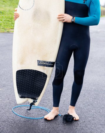 Ein junger Surfer im Neoprenanzug wird mit seinem Surfbrett gefangen genommen, voller Vorfreude auf die Umarmung des Meeres.