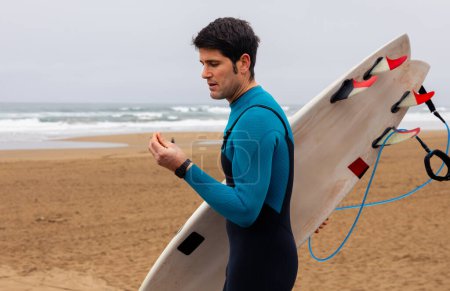 Téléchargez les photos : Surfeur se dirigeant vers la mer avec des bouchons d'oreilles pour la protection. - en image libre de droit