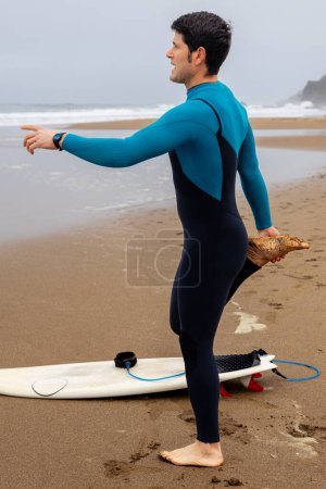 Foto de Surfista en la orilla calentándose por flexión antes de entrar en el mar, foto vertical. - Imagen libre de derechos