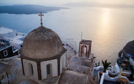 Ein ruhiger Sonnenuntergang taucht die traditionellen Kuppelkirchen Santorinis in ein Licht.