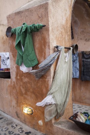 Téléchargez les photos : Des vêtements décontractés saisissent la brise chaude de la Méditerranée, accrochés à un mur vieilli de Santorin, illustrant le style de vie décontracté de l'île.. - en image libre de droit