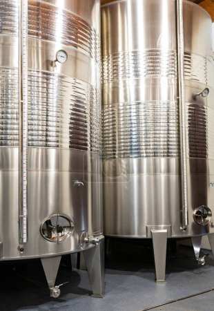 Foto de Tanques de acero inoxidable brillante utilizados para la fermentación y el envejecimiento del vino, mostrando la tecnología de vinificación moderna. - Imagen libre de derechos