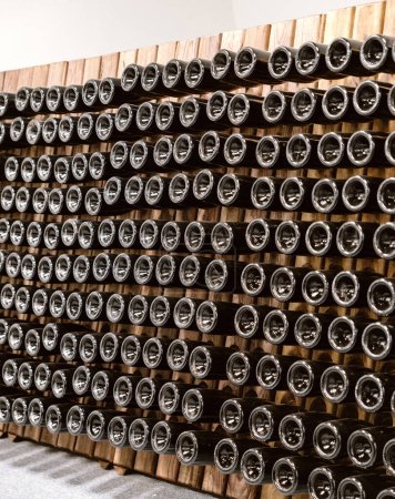 Eine geometrische Anordnung von Weinflaschen in einem modernen Keller, der darauf wartet, dass der perfekte Moment genossen wird.
