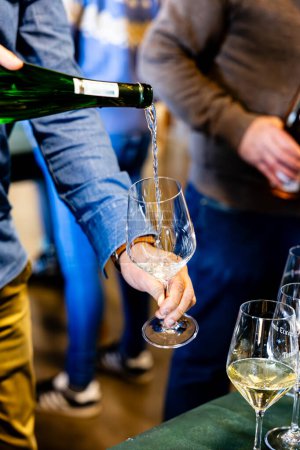 Un sommelier verse savamment du vin mousseux dans un verre de cristal lors d'une dégustation de vin, soulignant la finesse de la boisson.