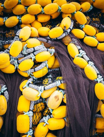 Flotteurs jaune vif enchevêtrés dans des filets de pêche traditionnels, capturés au port animé, symbolisant l'industrie maritime.