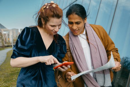 Un hombre y una mujer emparejan tecnología de viaje con cartografía tradicional para navegar por las calles de la ciudad.