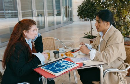 Téléchargez les photos : Deux professionnels participent à une discussion d'affaires sérieuse autour d'un café le matin dans un café extérieur. - en image libre de droit