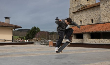 An action shot of a young skateboarder in mid-air performing a high ollie trick against a historical building backdrop.