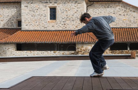 Téléchargez les photos : Plan d'action d'un skateboarder à l'équilibre dynamique, contrastant sport moderne sur fond de bâtiment traditionnel en pierre. - en image libre de droit