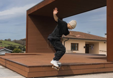 Skateboarder hält das Gleichgewicht bei einem Skateboarding-Trick auf einer Holzplattform, mit ländlicher Landschaft im Hintergrund.