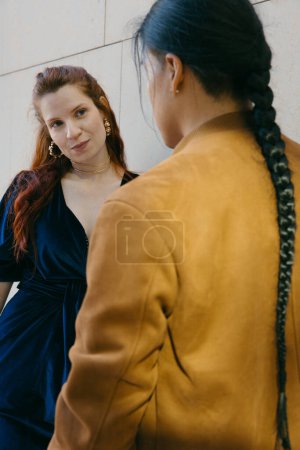 Photo for A young woman and Ecuadorian man with a braid share a relaxed moment, showcasing friendship in a vibrant urban setting. - Royalty Free Image