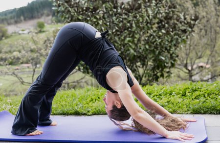 Photo for Female yogi perfects the Downward Dog pose, harmonized with nature's beauty - Royalty Free Image