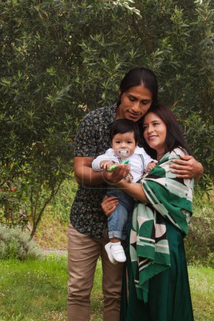 Ecuadorianische Mutter und Vater halten ihr Baby in einem grünen Garten und zeigen damit Liebe und familiäres Miteinander.