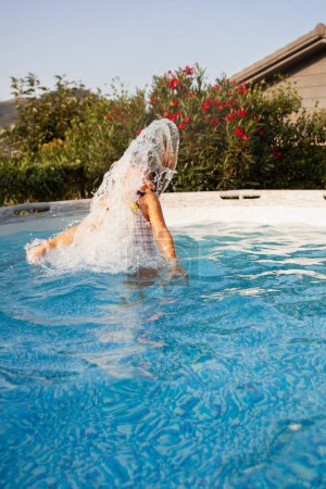 Téléchargez les photos : Fille faisant une pirouette dans l'eau de la piscine avec des cheveux - en image libre de droit
