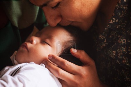 Téléchargez les photos : Un moment intime d'un père embrassant son bébé endormi, capturant l'essence de l'amour paternel et des soins. - en image libre de droit