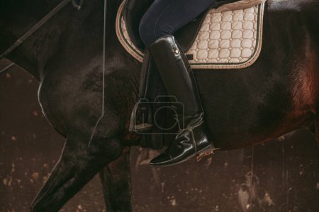 Photo for Detailed close-up of a rider's polished black riding boot in the stirrup, highlighting the elegance and precision of equestrian attire. - Royalty Free Image
