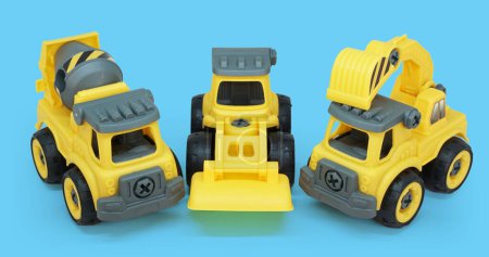 Téléchargez les photos : Jouet en plastique jaune de bétonnière et camion ecavator isolé sur fond bleu. véhicule de construction lourde. - en image libre de droit