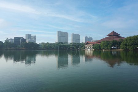 Téléchargez les photos : Certains immeubles d'appartements au loin et un bâtiment à côté d'un lac à l'Université d'Indonésie - en image libre de droit