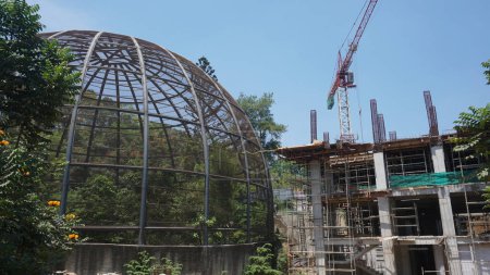 Large metal dome aviary for bird conservation next to a building construction site