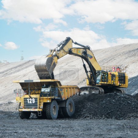 Téléchargez les photos : Grand camion minier jaune et excavatrice travaillant dans la carrière. Chargement du charbon dans le camion. - en image libre de droit