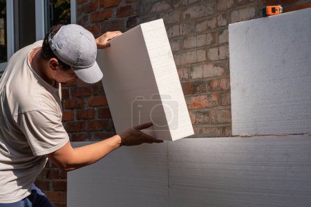 Un jeune homme isole les murs d'un immeuble