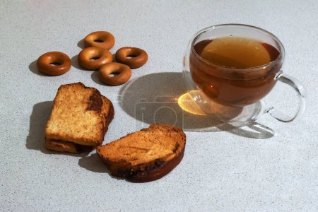 Composition with appetizing rusks (dry bagels) and a mug of tea on a light gray table