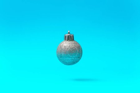 Photo for Silver Christmas Ball Ornament Floating in Mid-Air on a Blue Background - Royalty Free Image