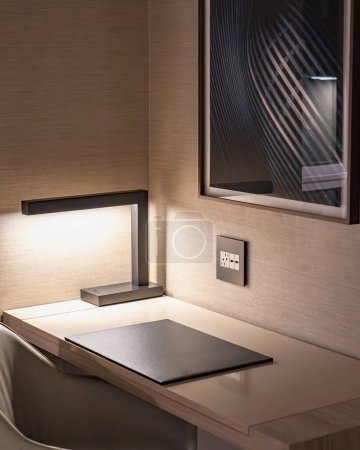 Photo for Work desk in a modern hotel room with moody lighting from a desk lamp - Royalty Free Image