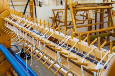 Téléchargez les photos : Gros plan d'un métier à tisser au sol chevilles de gauchissement sectionnelles dans un atelier de tissage textile - en image libre de droit
