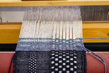 Photo for Close-up of a floor loom with black white and blue hand-woven textiles - Royalty Free Image