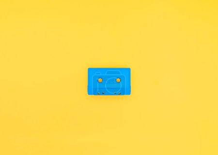 Téléchargez les photos : Cassette bleue rétro et vintage centrée sur un fond jaune vif. Studio photographié avec espace de copie. - en image libre de droit