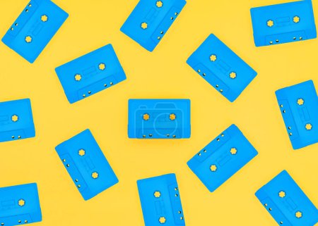 Téléchargez les photos : Cassettes bleu rétro dispersées sur un fond jaune vif. Studio photographié avec espace de copie. - en image libre de droit