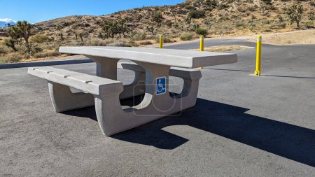 Téléchargez les photos : ADA Table de pique-nique en ciment accessible en fauteuil roulant dans une aire de stationnement d'une aire de loisirs désertique - en image libre de droit