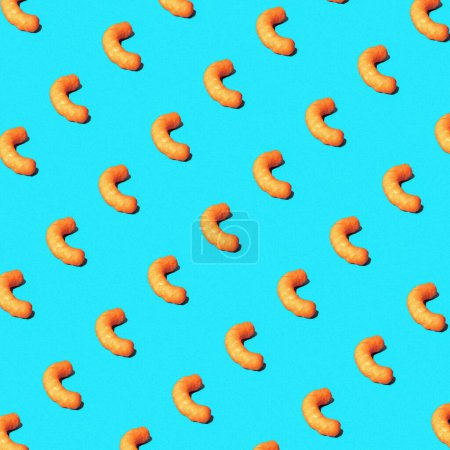 Photo for Cheese puffs in a repeating pattern on a brightly lit studio blue background. - Royalty Free Image