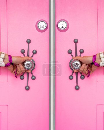 Photo for Pink door with a woman's hands holding the doorknobs in Palm Springs, California - Royalty Free Image