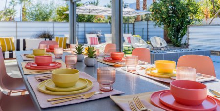 Photo for Backyard patio and dining table with bowls, plates, glasses, and silverware outdoors - Royalty Free Image